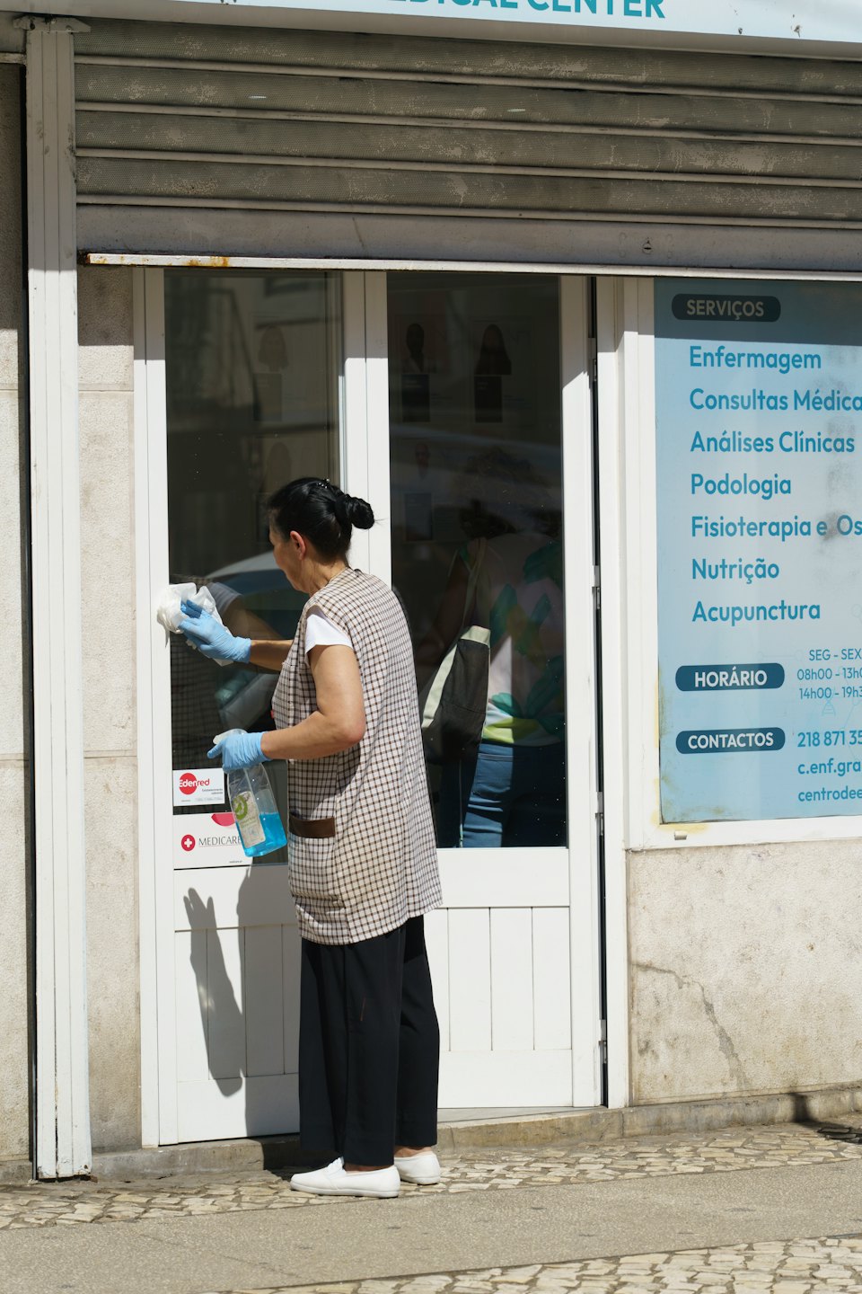 Person in uniform cleans glass door of medical center.