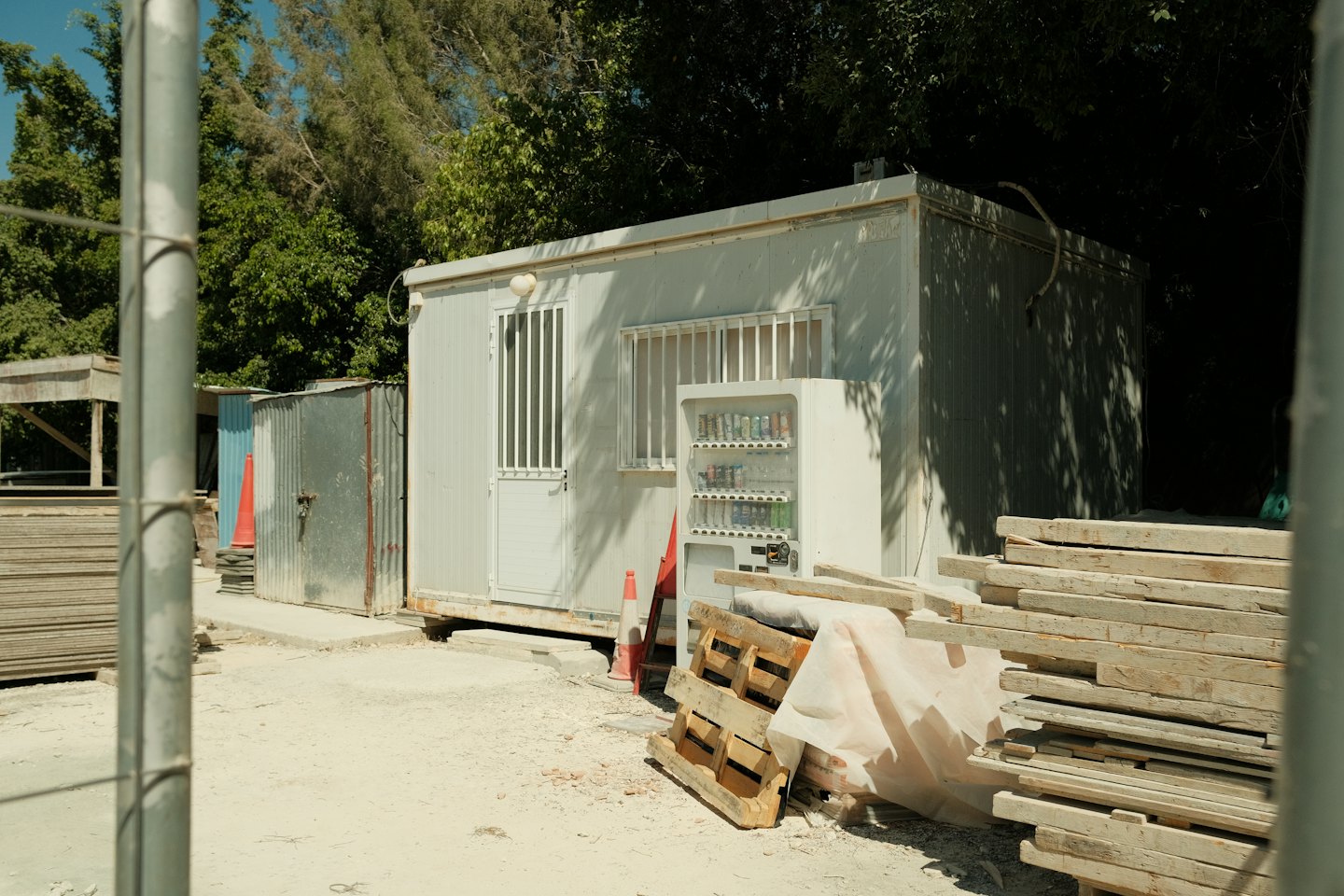 Portable construction office cabins sit behind a metal fence.