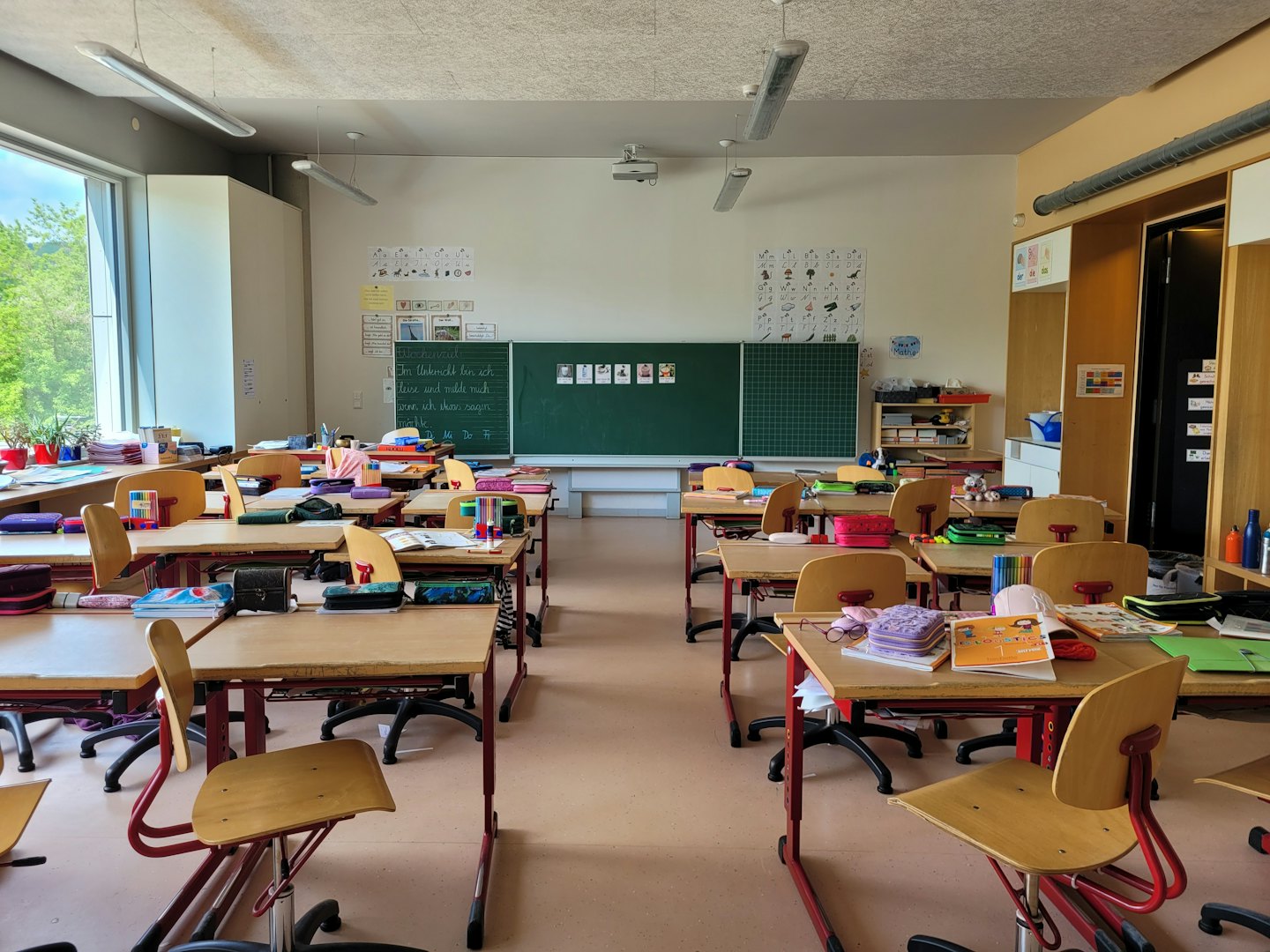 Empty modern classroom with rows of desks and a chalkboard.